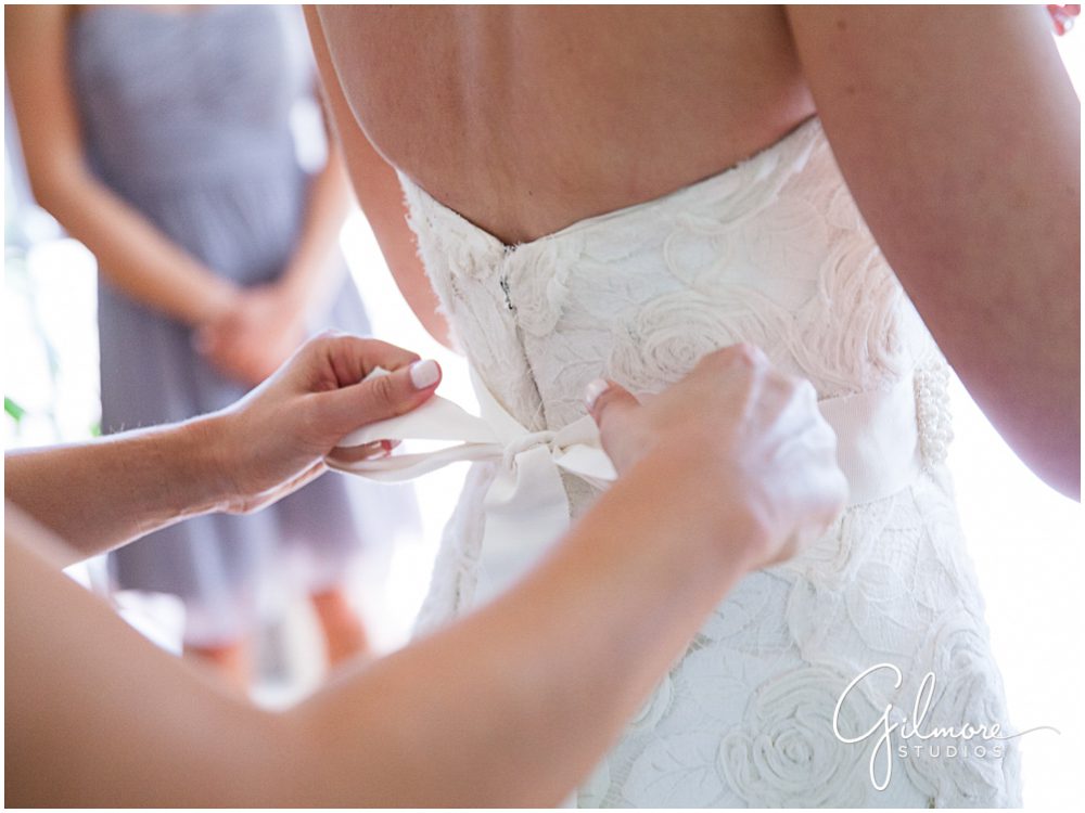 tieing the bow on the bride's wedding dress