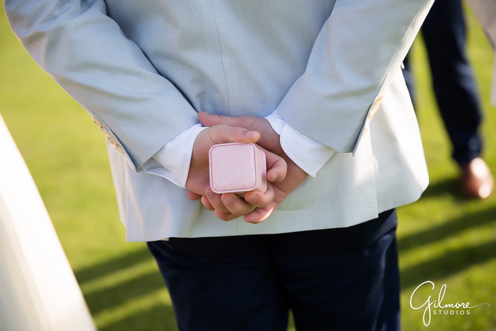 groomsman holding the wedding ring box behind his back