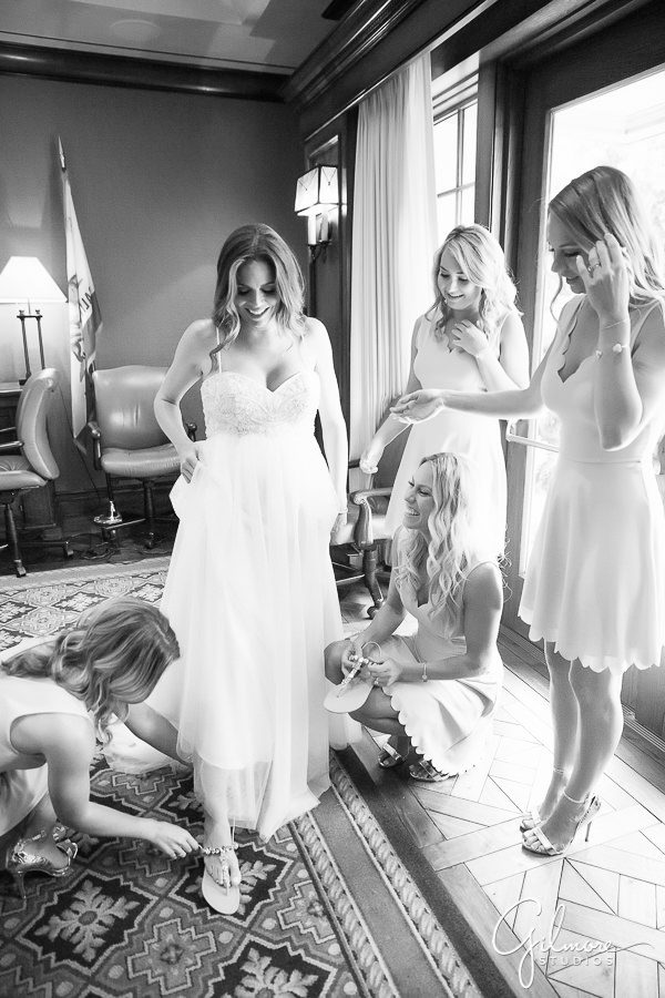 bridesmaids helping the bride with her dress and shoes before the wedding
