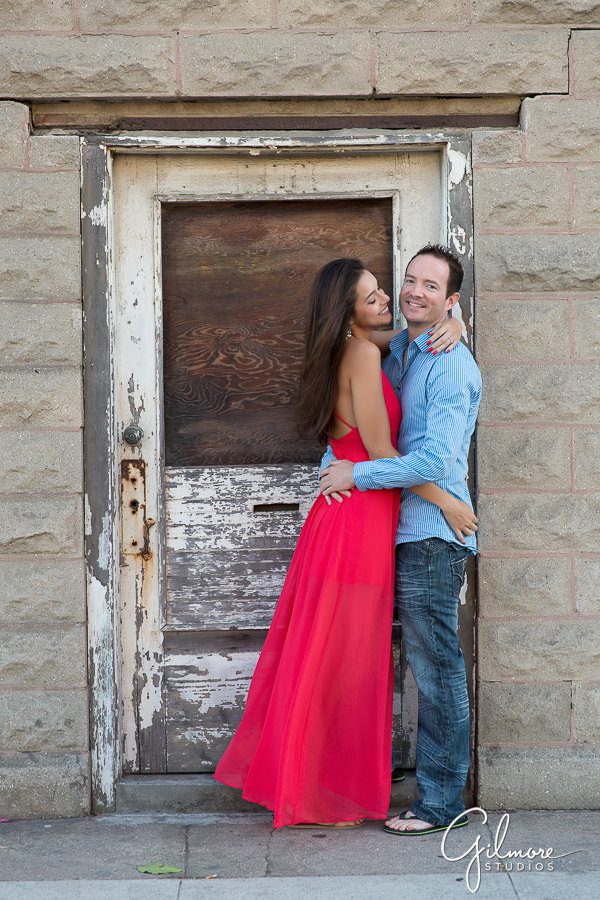Engagement session next to a rustic door in Huntington Beach