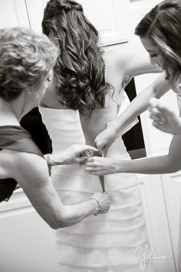 Mother and bridesmaids helping the bride get ready for her wedding