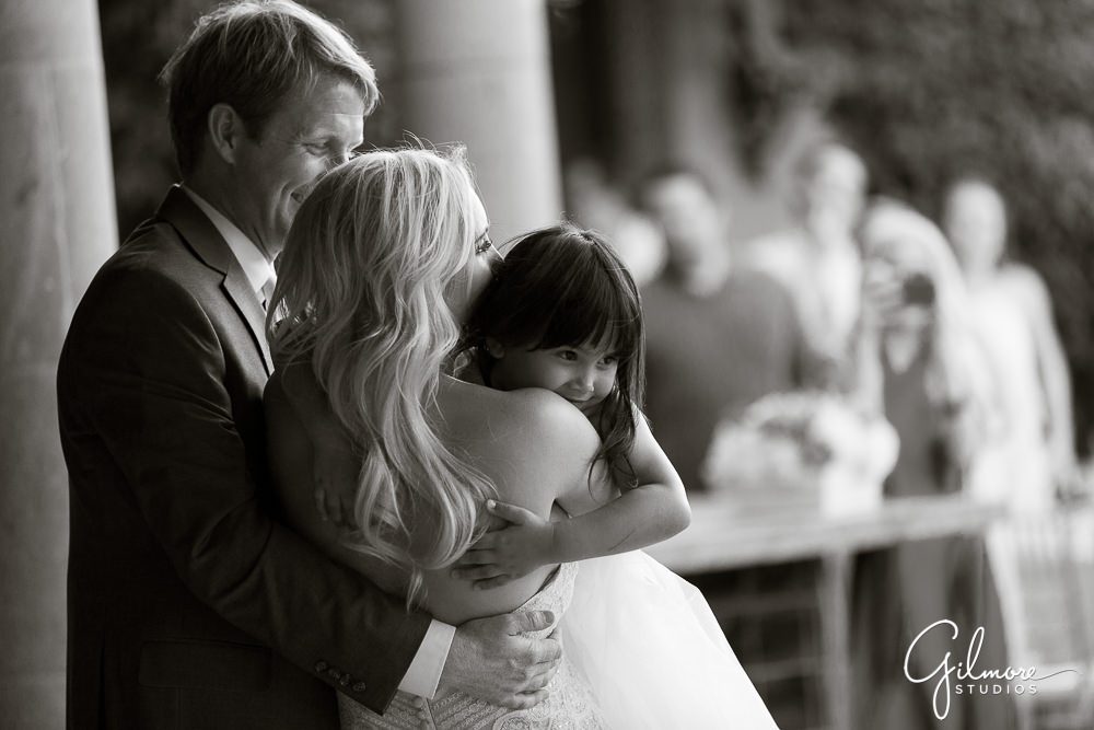 Cute photo of the bride and groom hugging their flower girl