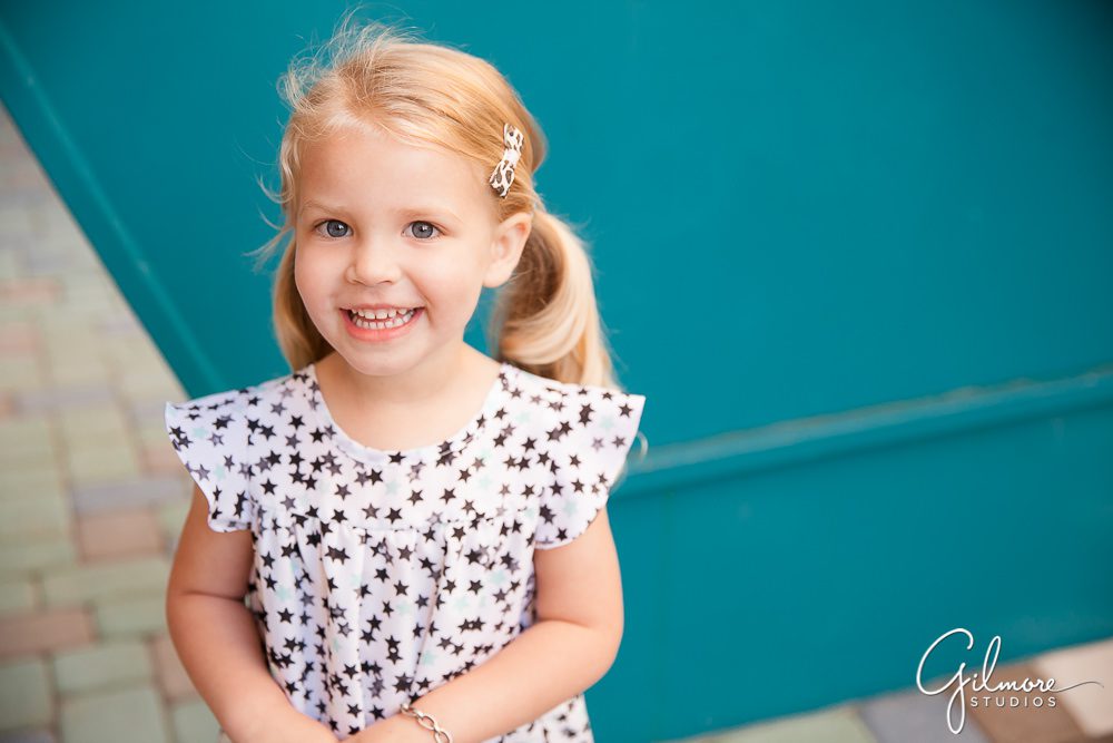 children's portrait photo on a bright teal blue wall