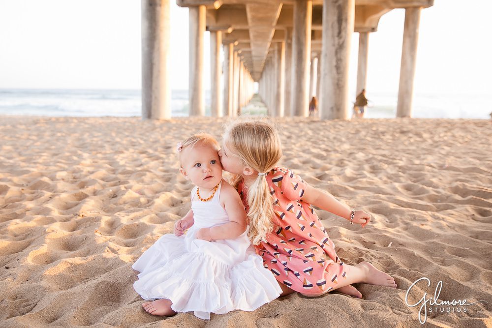 sisters loving eachother on the sand in Huntington Beach