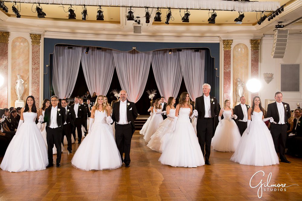 Dads dance with their daughters in white debutante dresses.