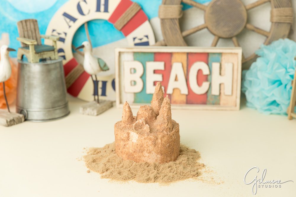 Beach props surrounding the sand castle birthday cake