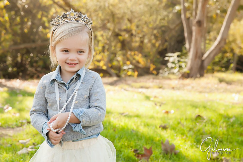 Little girl smiles for her princess portrait at the park