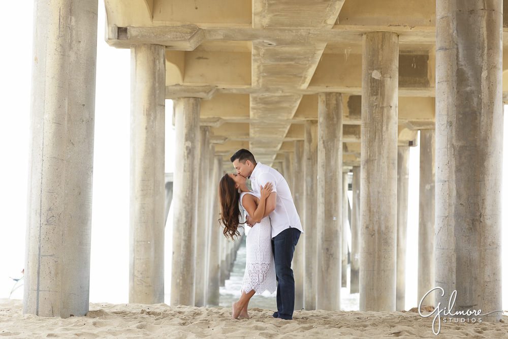 kissing under the pier in Huntington Beach, CA