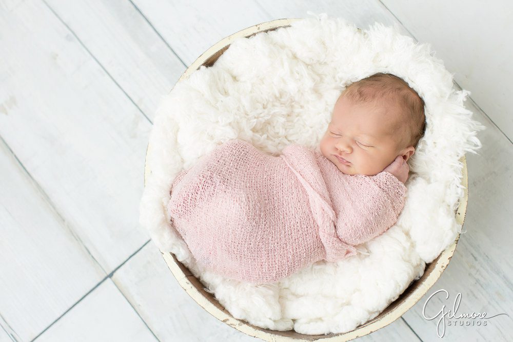 newborn posing, bowl, wood floor, pink wrap, newborn photography