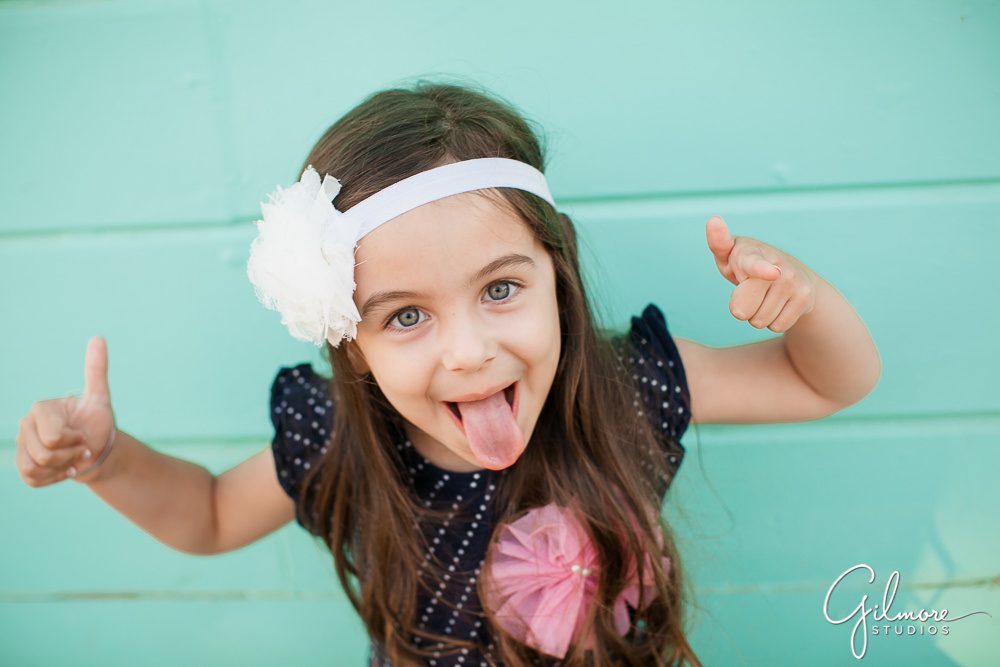 funny candid portrait of a 4 year old girl next to a teal blue wall at Crystal Cove