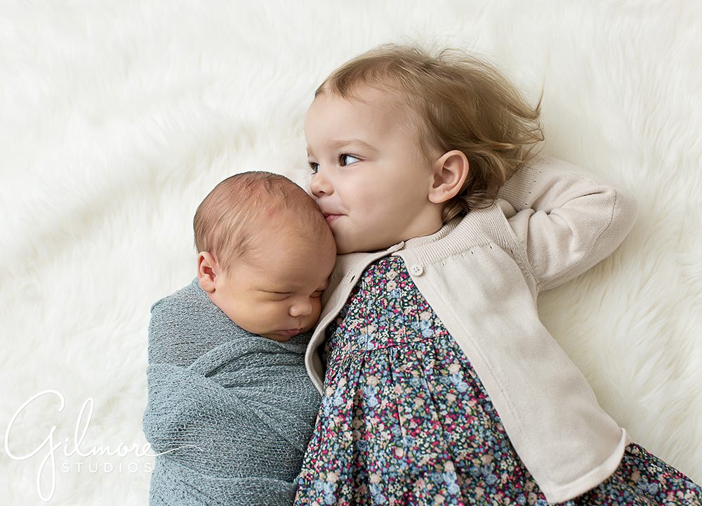 baby laying with his big sister, kisses, newborn photo