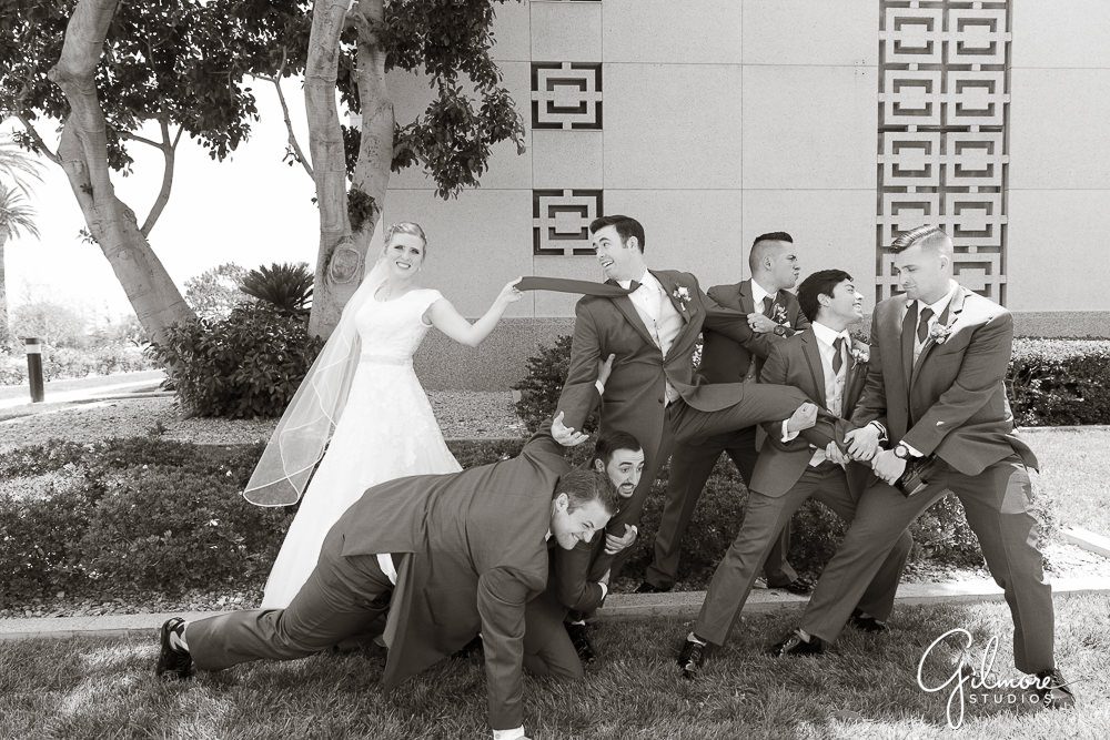 fun pose, groomsmen trying to take the groom from the bride
