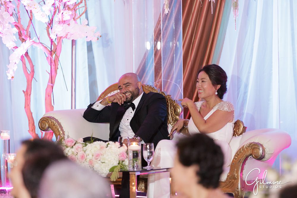 couple sits at their sweetheart table while listening to wedding speeches