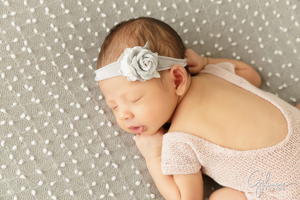 newborn baby girl with silver headband and pink outfit