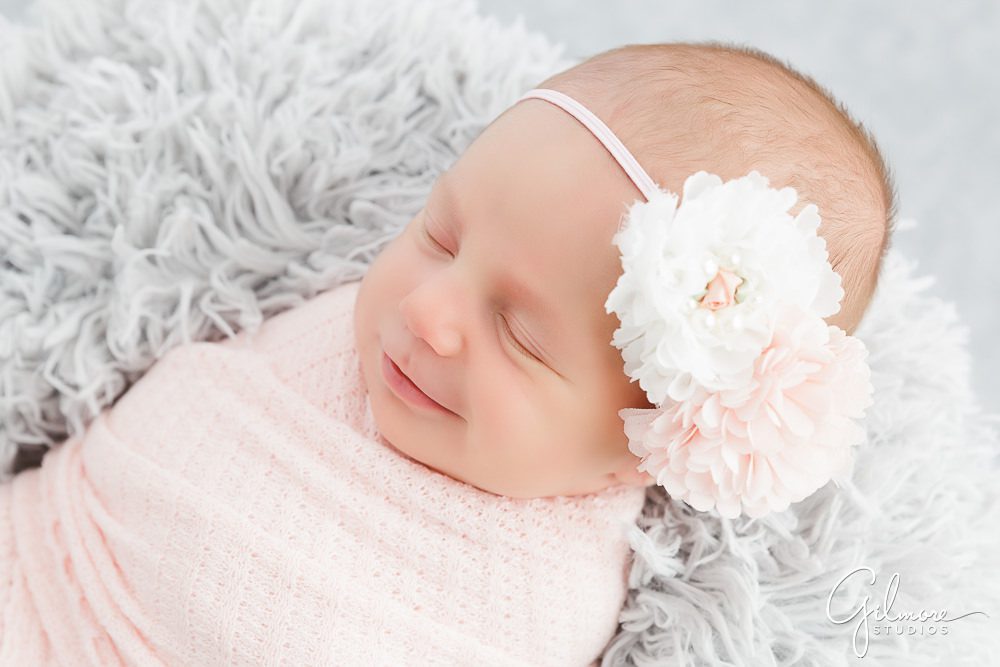 Maternity and Newborn Photography, smiling baby, grey blanket background, portrait studio, session package, headband, flowers, pink swaddling cloth, sleeping, asleep, outfit, family