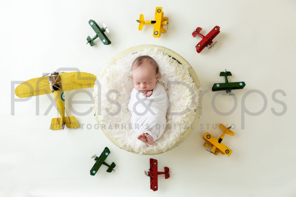 Newborn Digital Backdrops styled by Pixels and Drops with circular planes all around the world colorful aviator on white background and white faux fur in ivory bowl