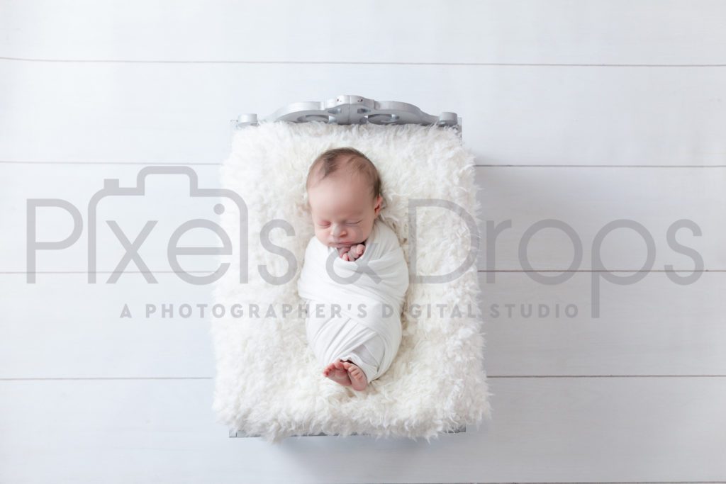 Newborn Digital Backdrops styled by Pixels and Drops with a fancy silver brushed newborn bed. The ornate headboard compliments the white faux fur that will soften up newborn photo. White plank boards accent the decorative headboard