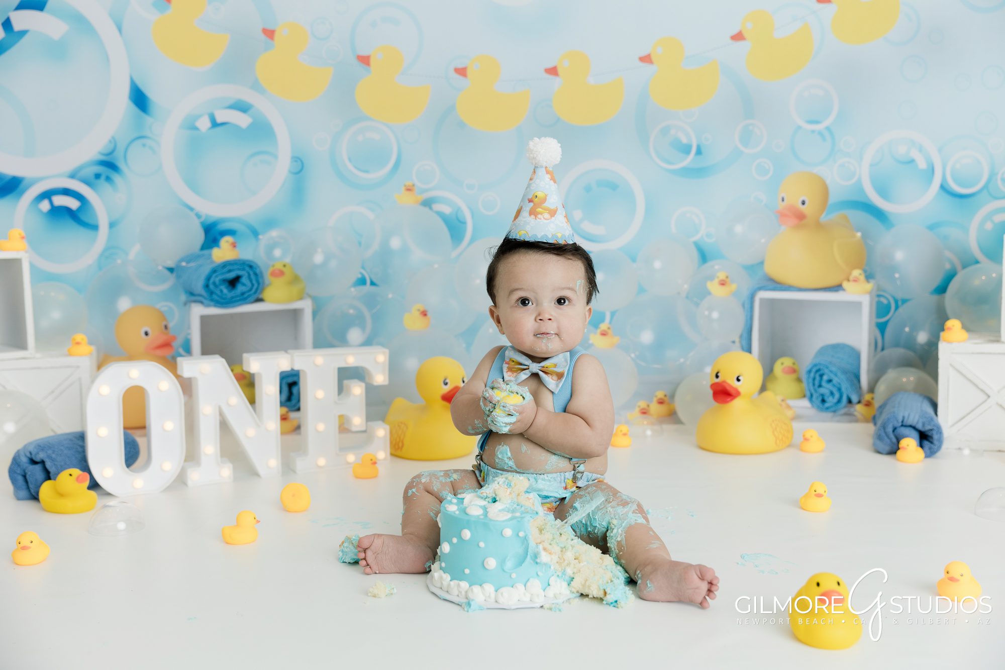 Rubber Ducky Cake Smash Photography Session, Gilbert Children's Photographer, Queen Creek Baby Photo Studio, Gilmore Studios, Yellow rubber ducky, bath, bubbles, set design, props, baby outfit, 1 year old, one year old boy, cake, bowtie, photo