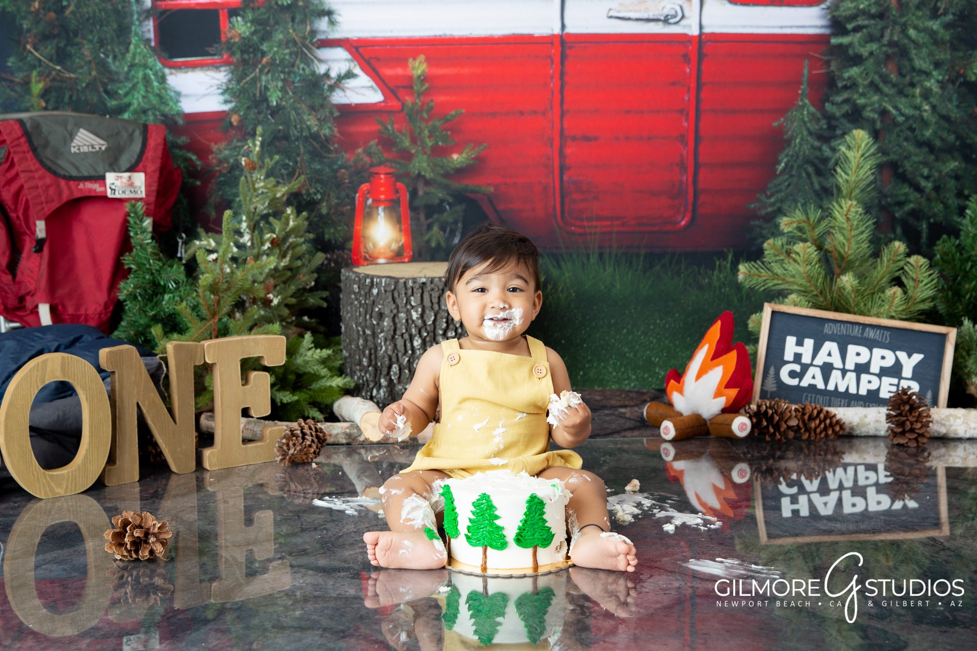 Camping themed cake smash by Gilmore Studios, camper, trailer, woods, forest, outdoors, camp fire, happy camper, pine trees, great outdoors, one year old, 1 year old, first birthday, photographer, background, set design, cakes, smashcake