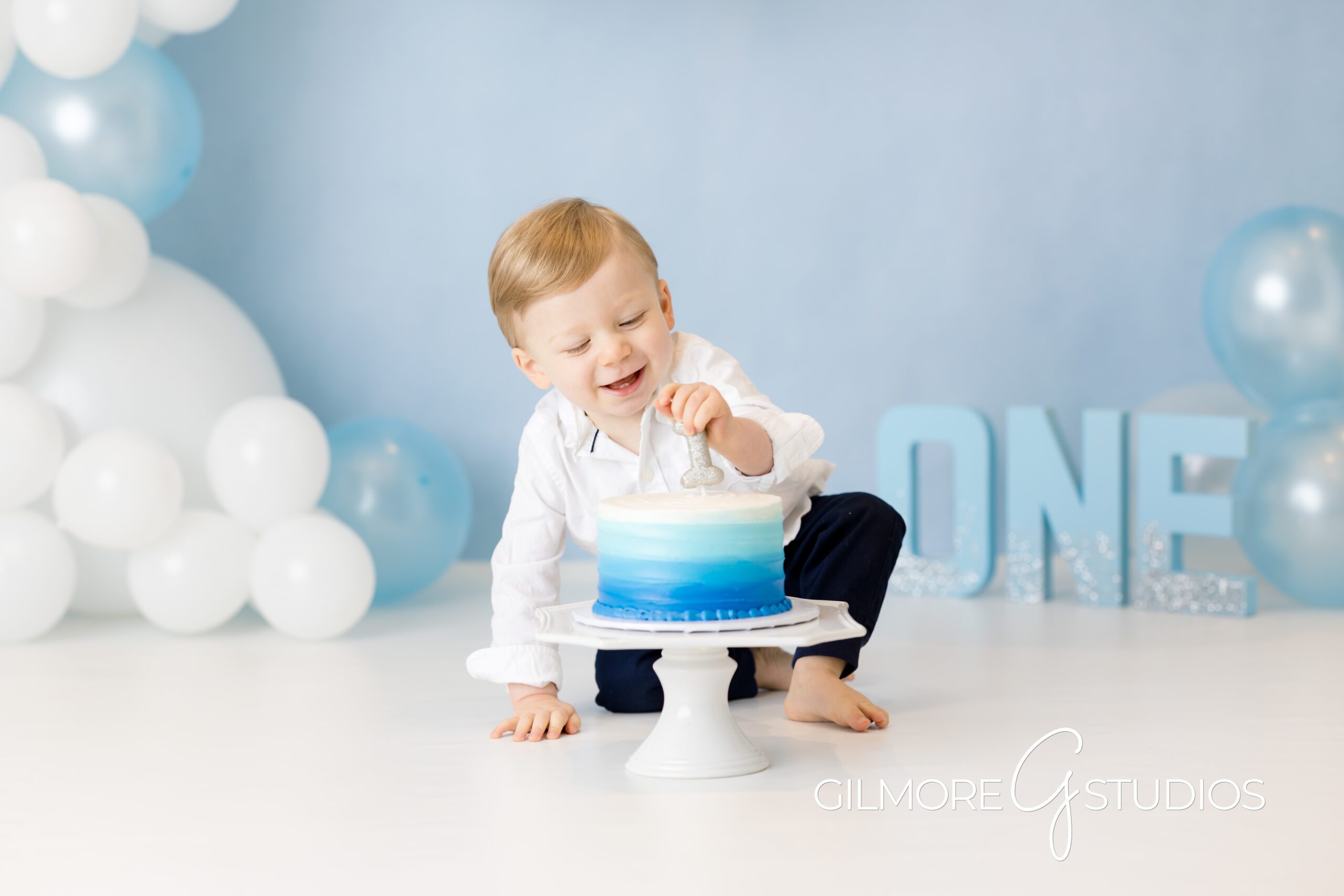 Simple 1st Birthday Cake Smash - Gilbert, AZ Photographer, baby on blue and white balloon background, brother, first birthday, cake smash photo shoot, Gilmore Studios, blue and white cake