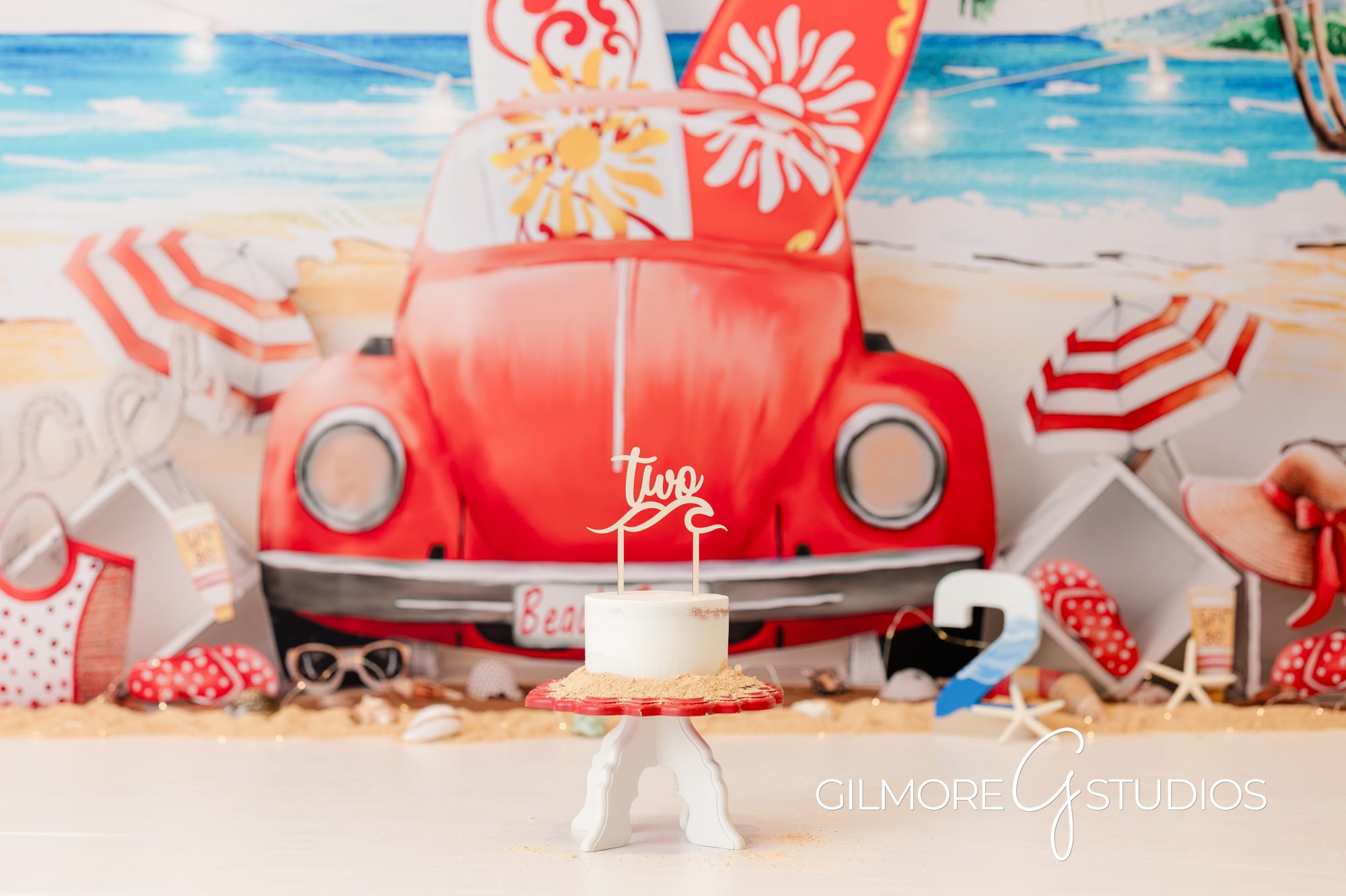 Summer Cake Smash VW Bug Beetle Newport Beach, beach, yellow polka dot bikini, gilmore studios, cake smash, little girl 2nd birthday, happy bday, child photography, vw beetle, vw bug, volkswagon, red and white, beach, waves, sand, white cake, vanilla frosting, buttercream, excited, ponytail, white romper, surfboards, yellow and red