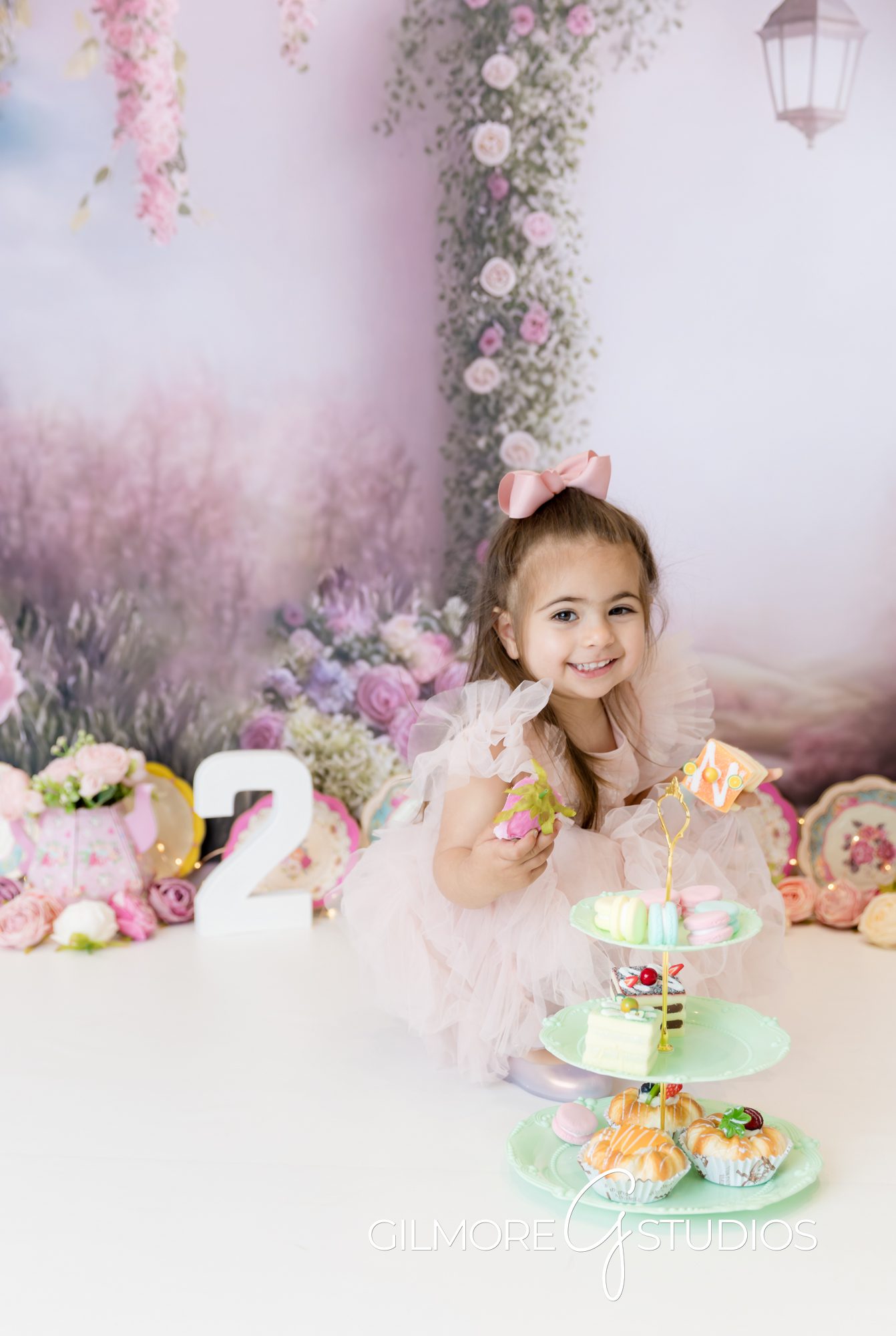 tea party cake smash, little girl, little girl smiling, pink dress, pink bow, indoor photography, indoor photo shoot, tea party treats, cake, gilmore studios