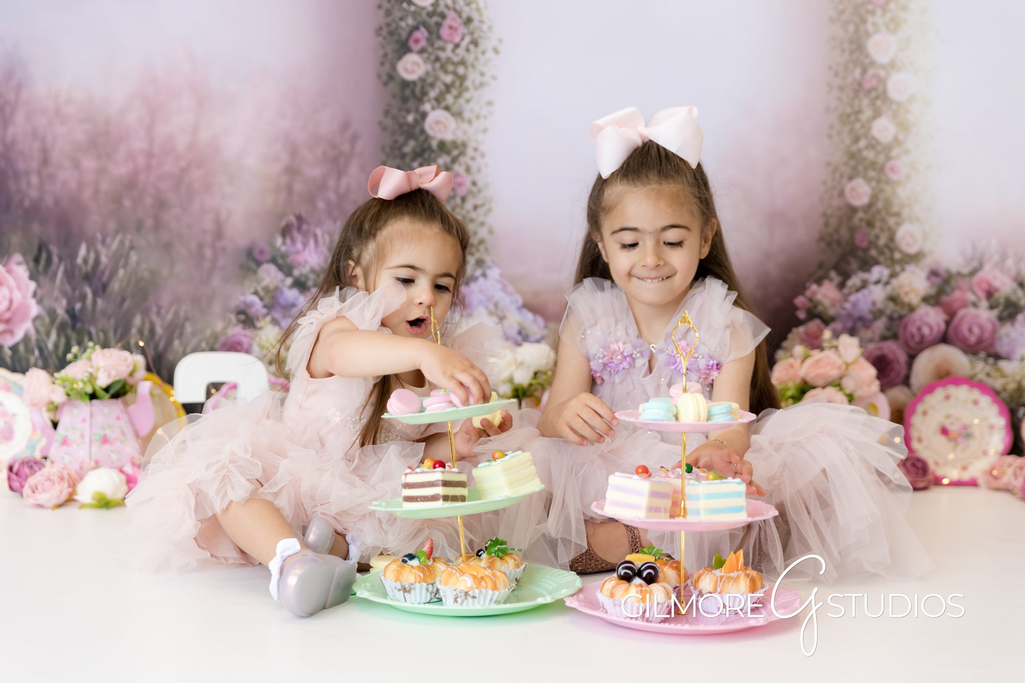 tea party cake smash, pink bows, little girls, big sister, little sister, tea party, eating cake, holding sweets, smiling, indoor photography, cake smash, gilmore studios