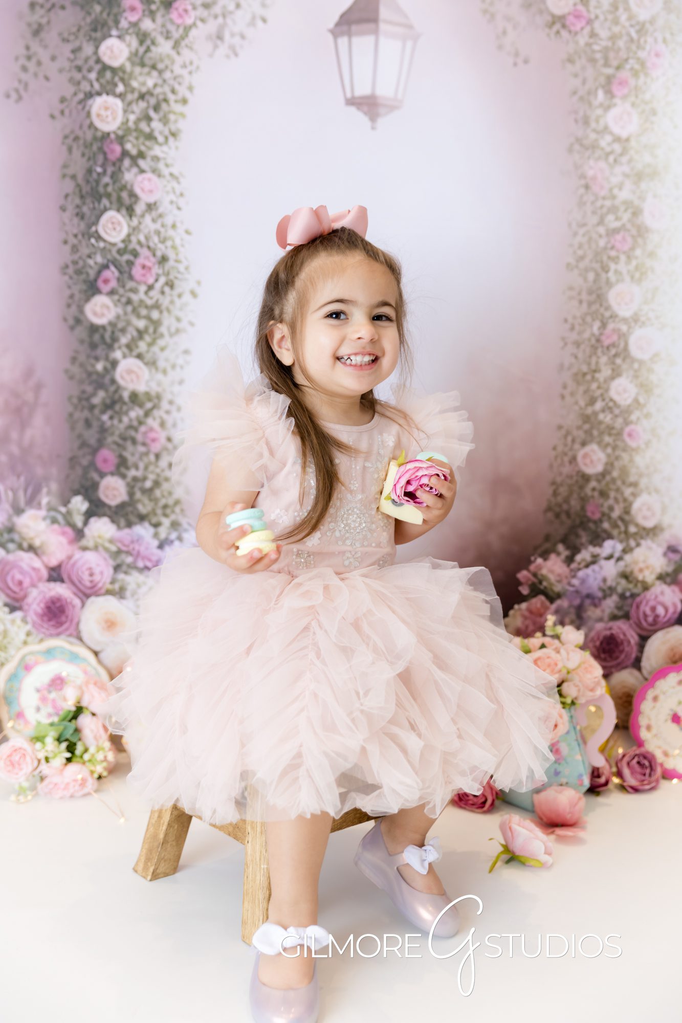tea party cake smash, little girl, pink dress, pink bow, holding treats, smiling, gilmore studios