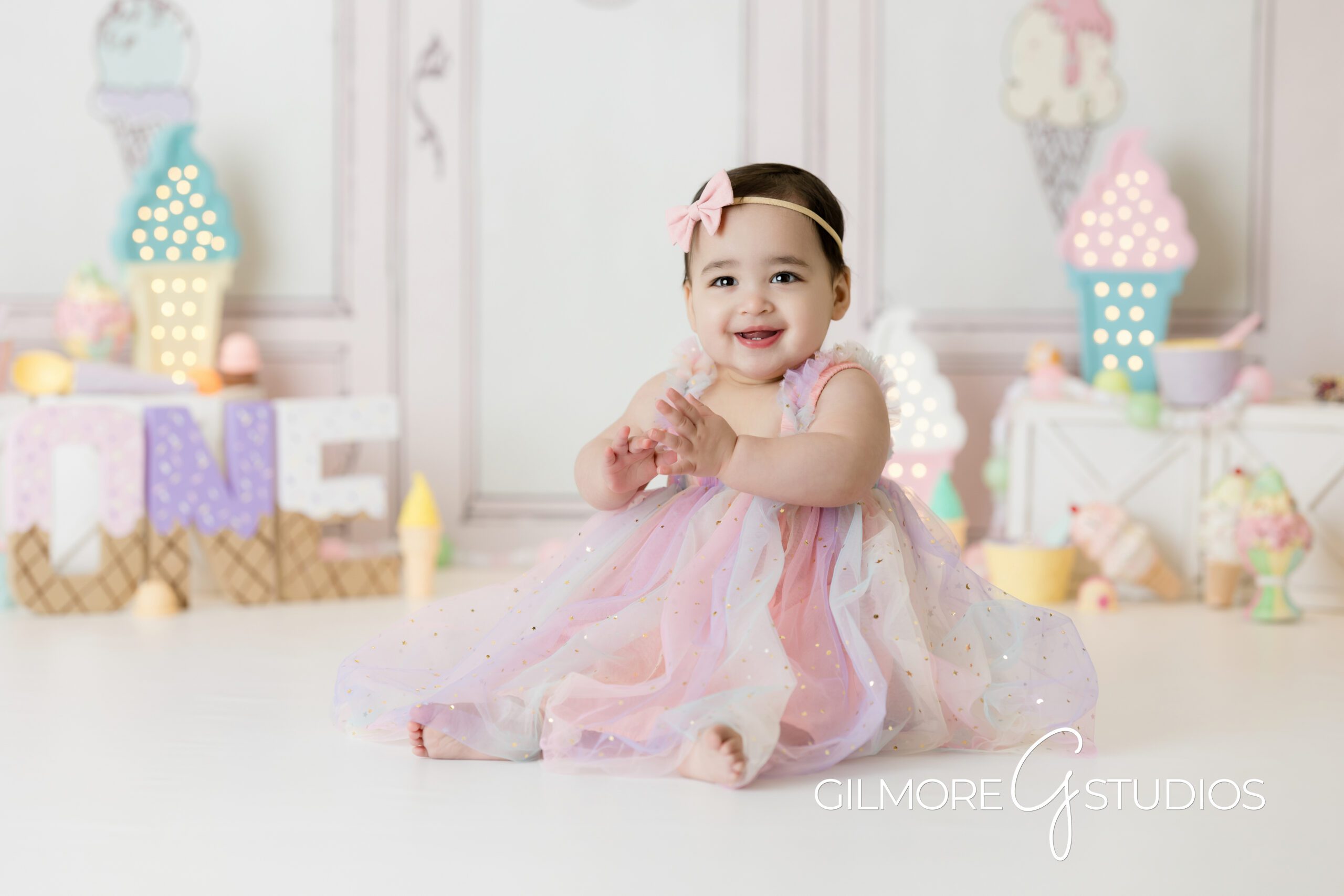 ice cream themed cake Smash, little girl, pink bow, pink dress, clapping, sitting up, cake Smash, Gilmore Studios