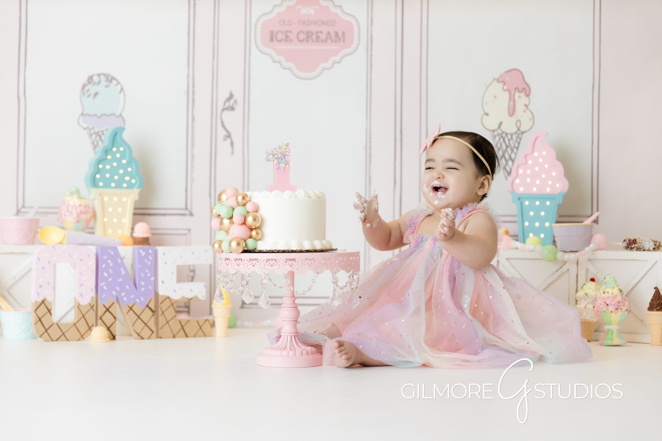 ice cream theme cake Smash, little girl, little girl laughing, pink dress, white cake, ice cream parlor, ice cream themed, cake Smash, photography, Gilmore Studios