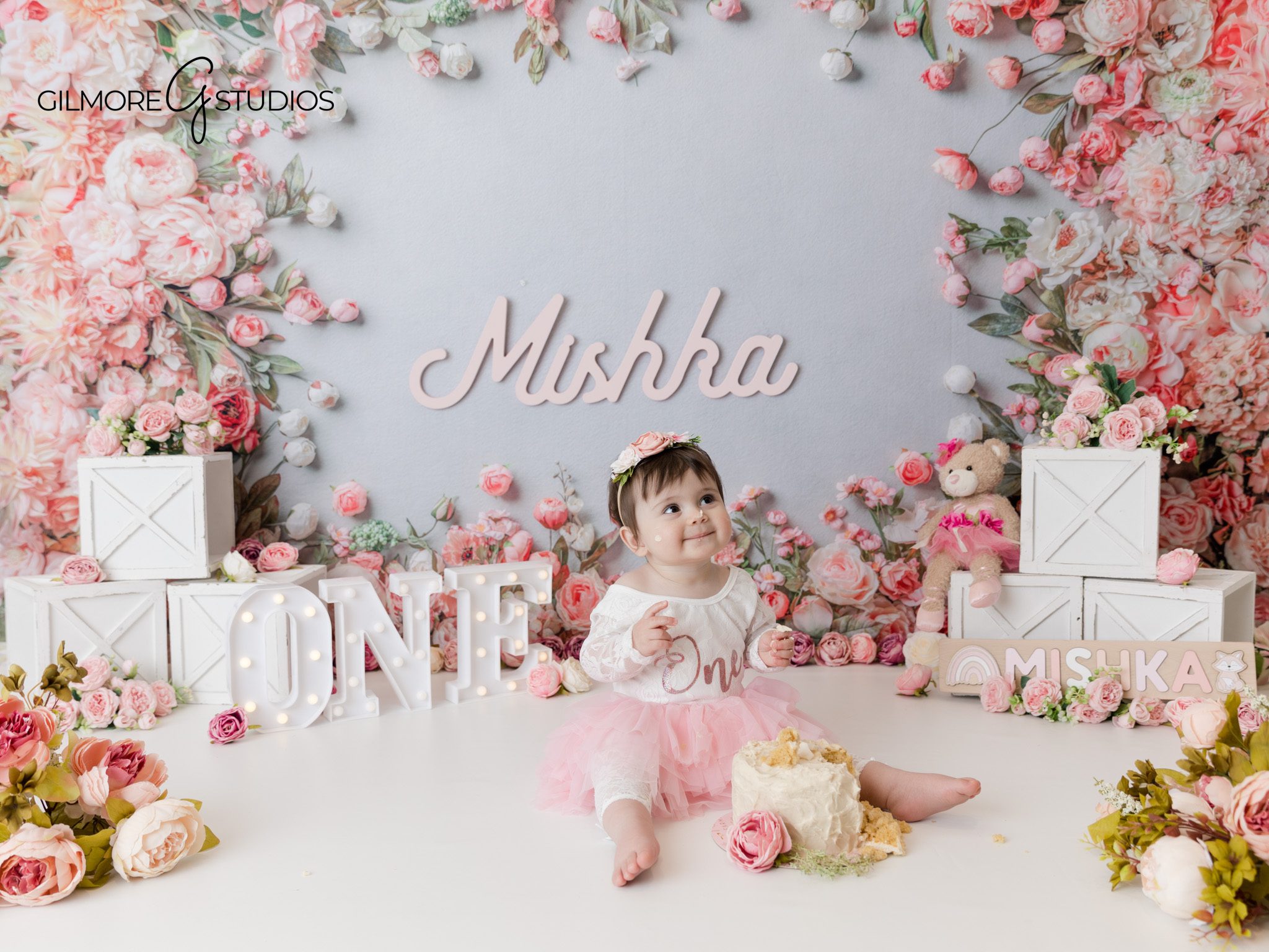 Baby girl holding cake topper, soft floral backdrop, Orange County studio