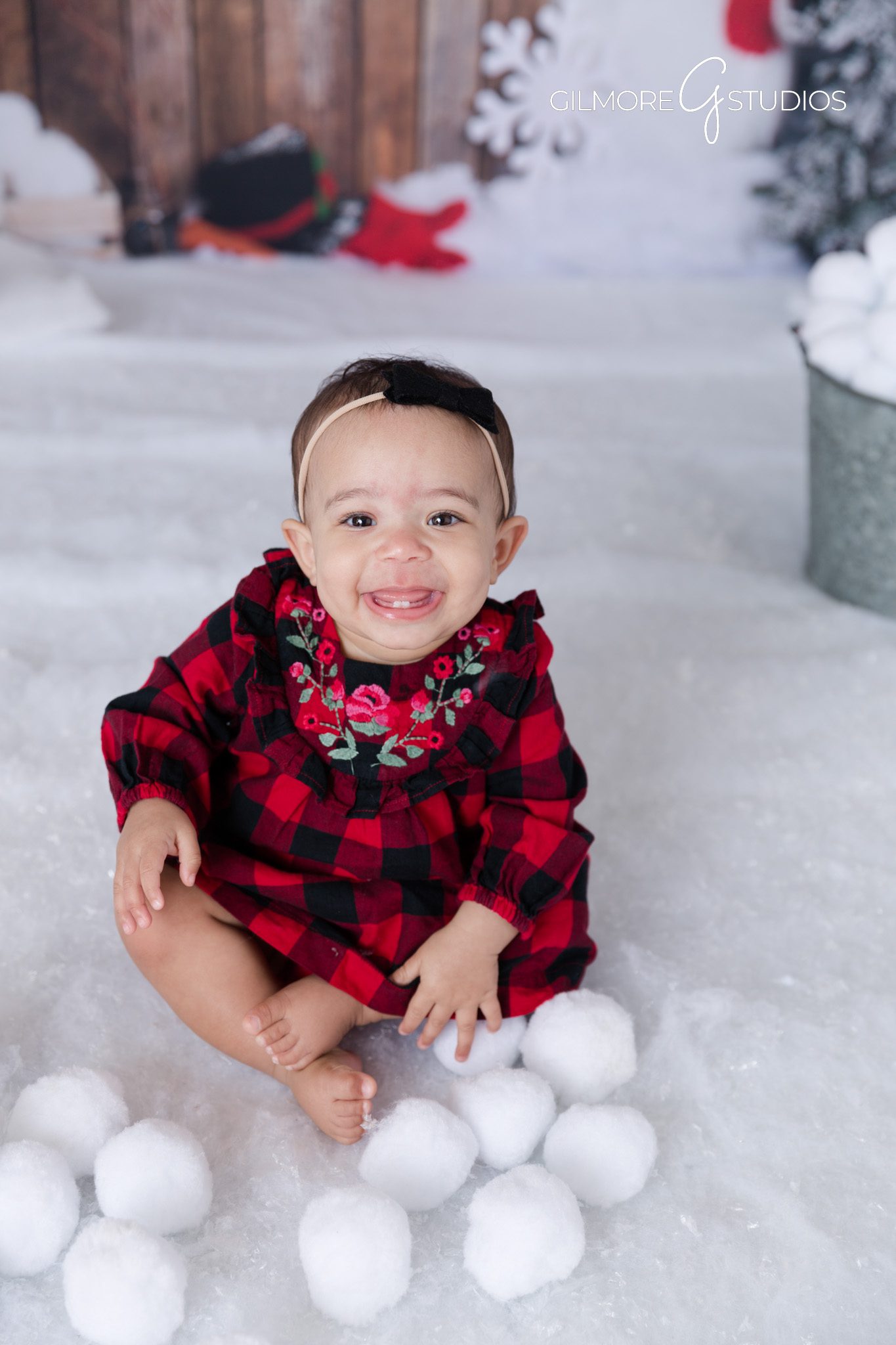 Smiling baby holding snowball – studio winter theme