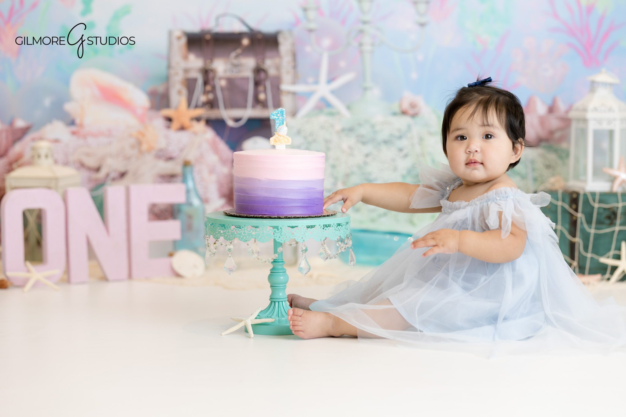 Under-the-sea themed cake smash photography for baby girl turning one.

Baby portrait photography capturing close-up of frosting-covered hands.
