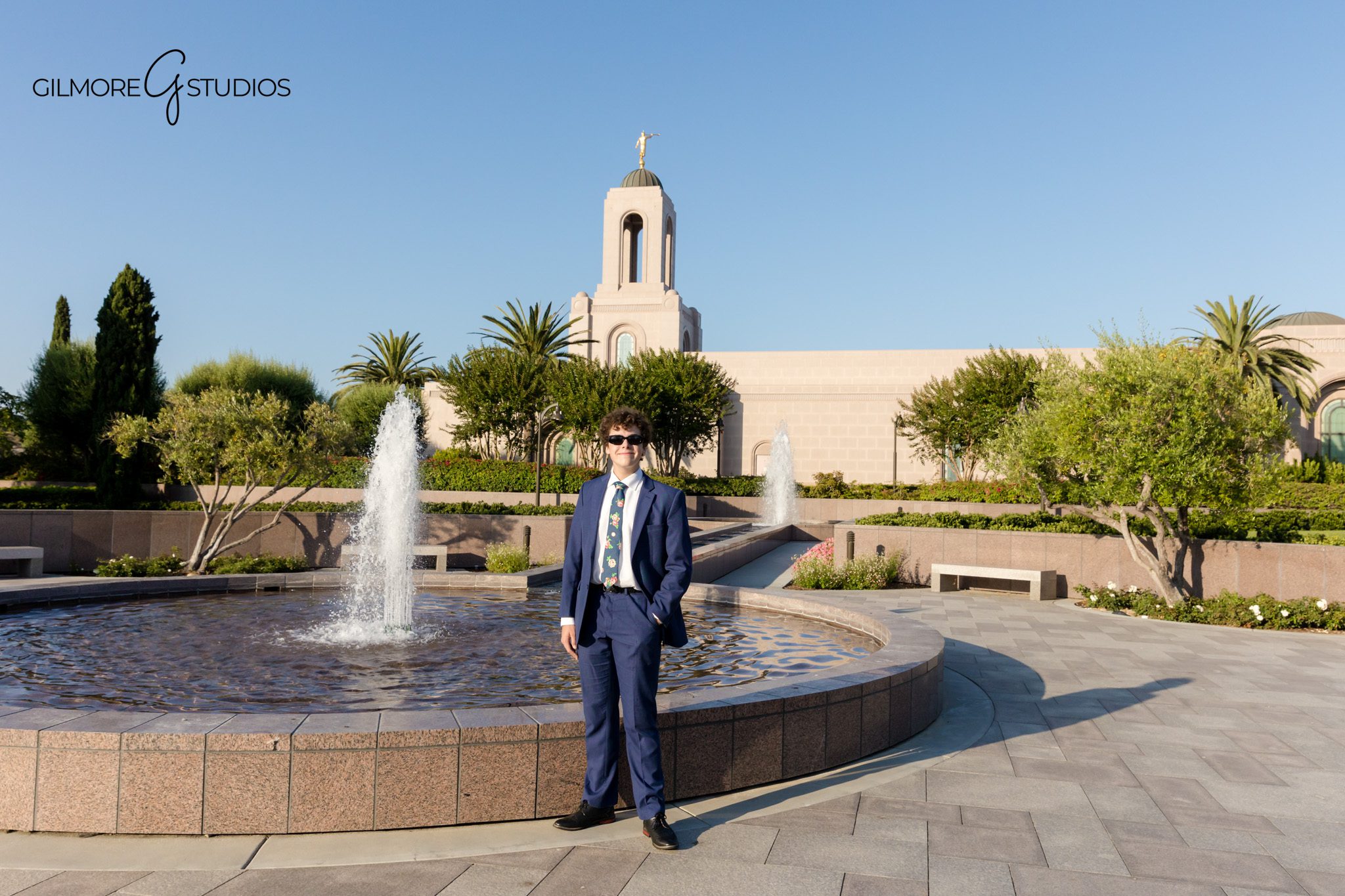Missionary photography showing elder adjusting suit collar.

Sister missionary portrait in natural coastal greenery.