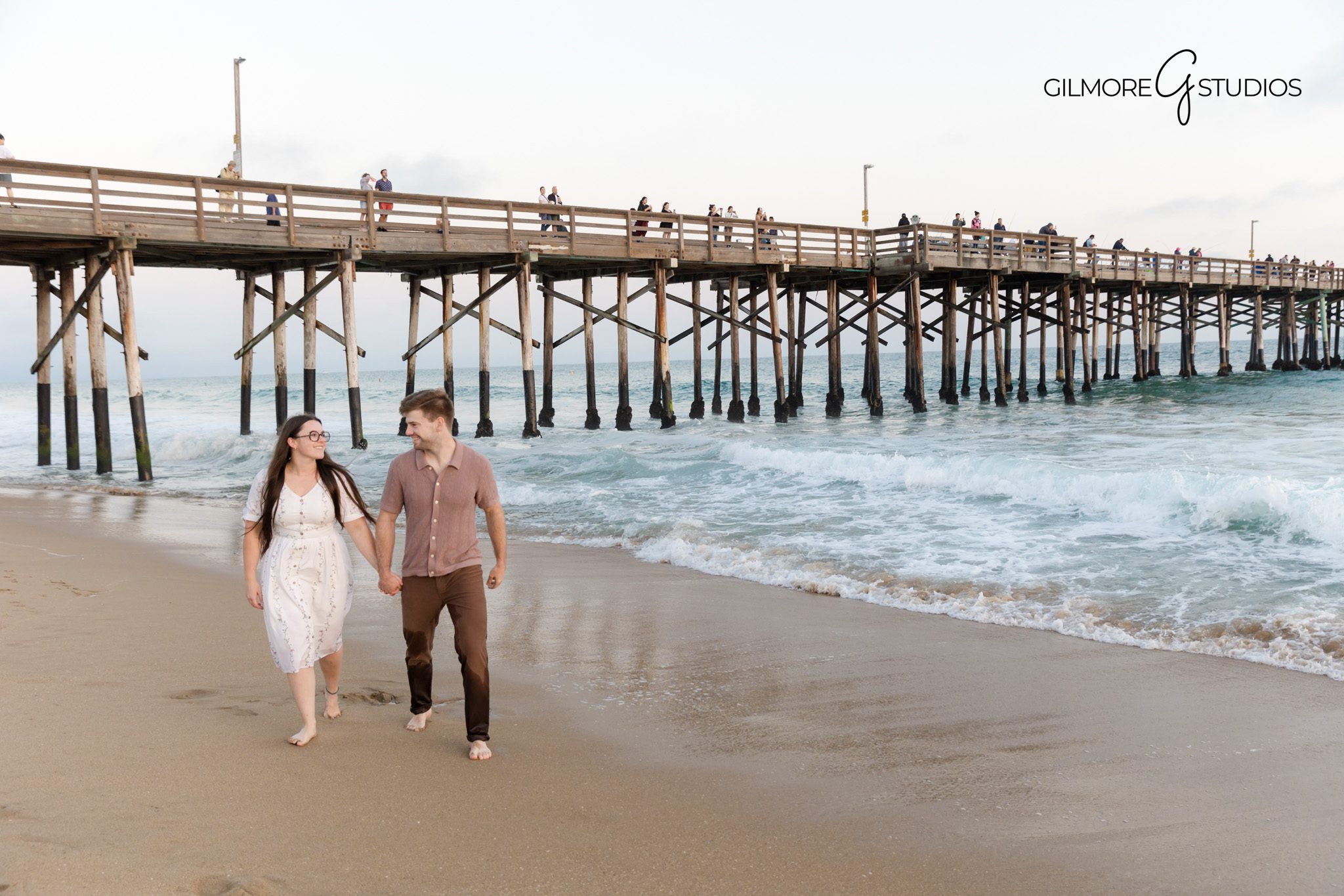 Newport Beach portrait photography with soft warm lighting.

Family photographer capturing candid beach walk under Newport Pier.