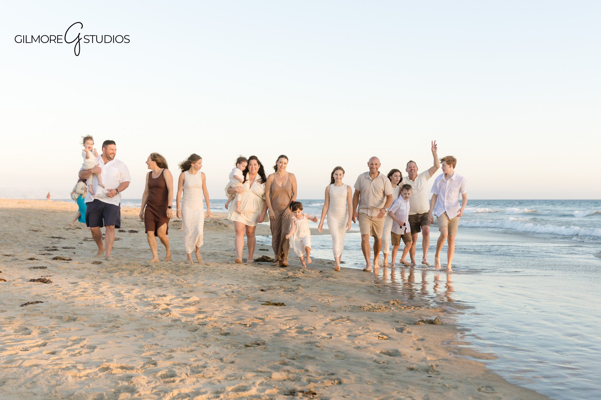 Gilmore Studios photographing extended family at Newport Beach Pier.

Warm sunset portrait photography of family holding hands at the waterline.
