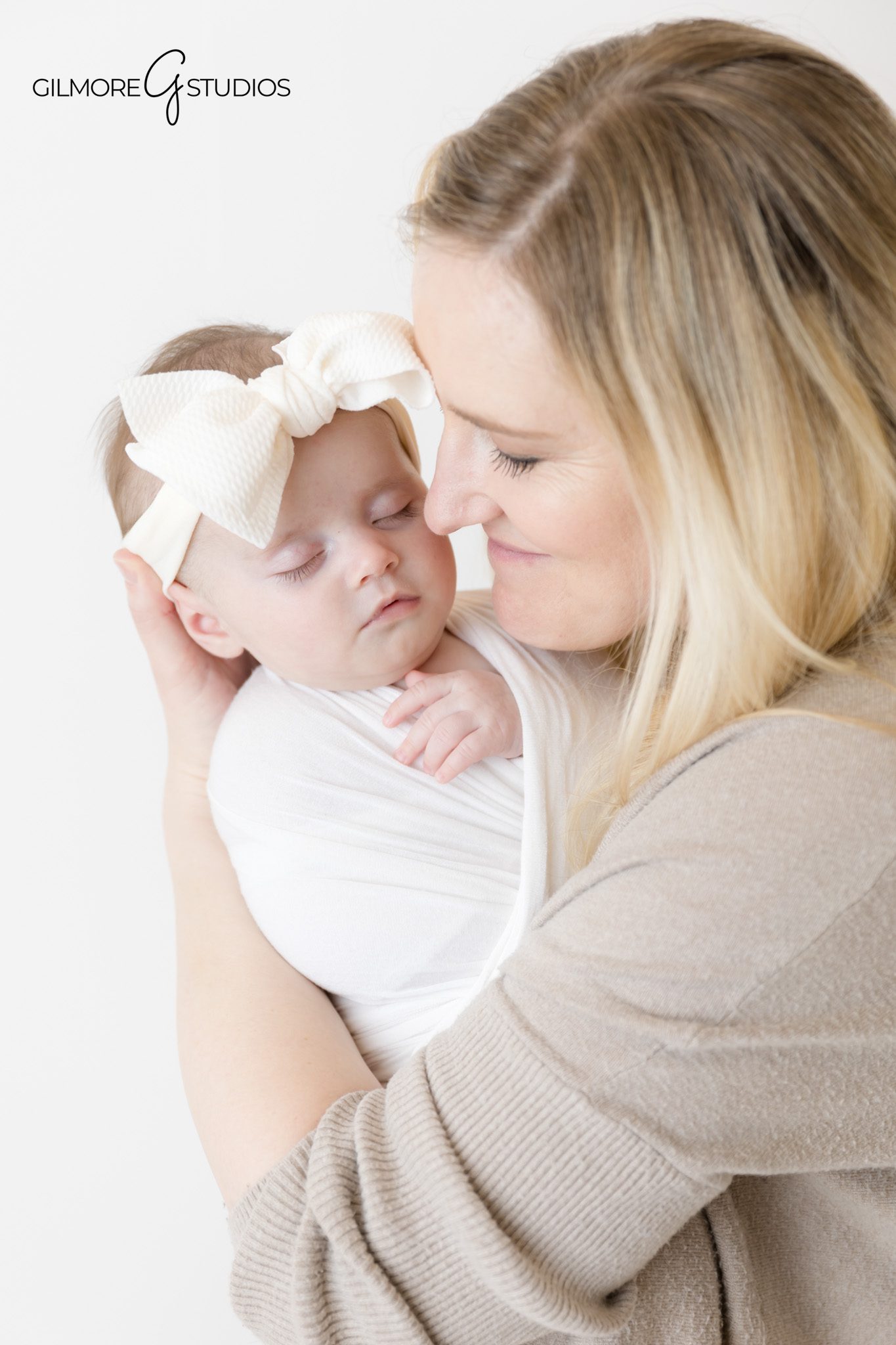 Two month old milestone photography in clean white studio background.
Portrait photographer capturing bright eyed two month old baby.
