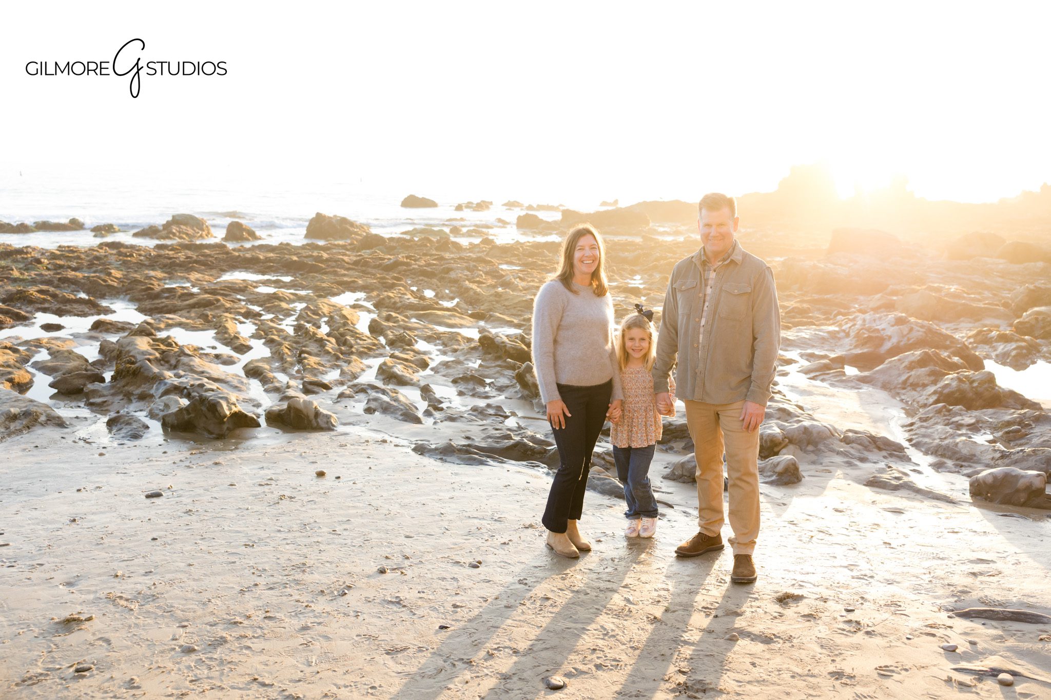Professional family photographer documenting playful moments by the ocean.

Corona del Mar portrait photography of parents walking with children on the sand.