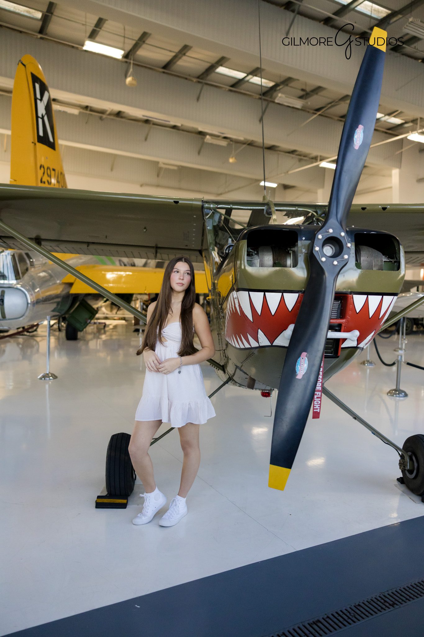 Close up senior portrait captured by Gilmore Studios OC
Senior girl sitting near aircraft for stylish indoor portrait