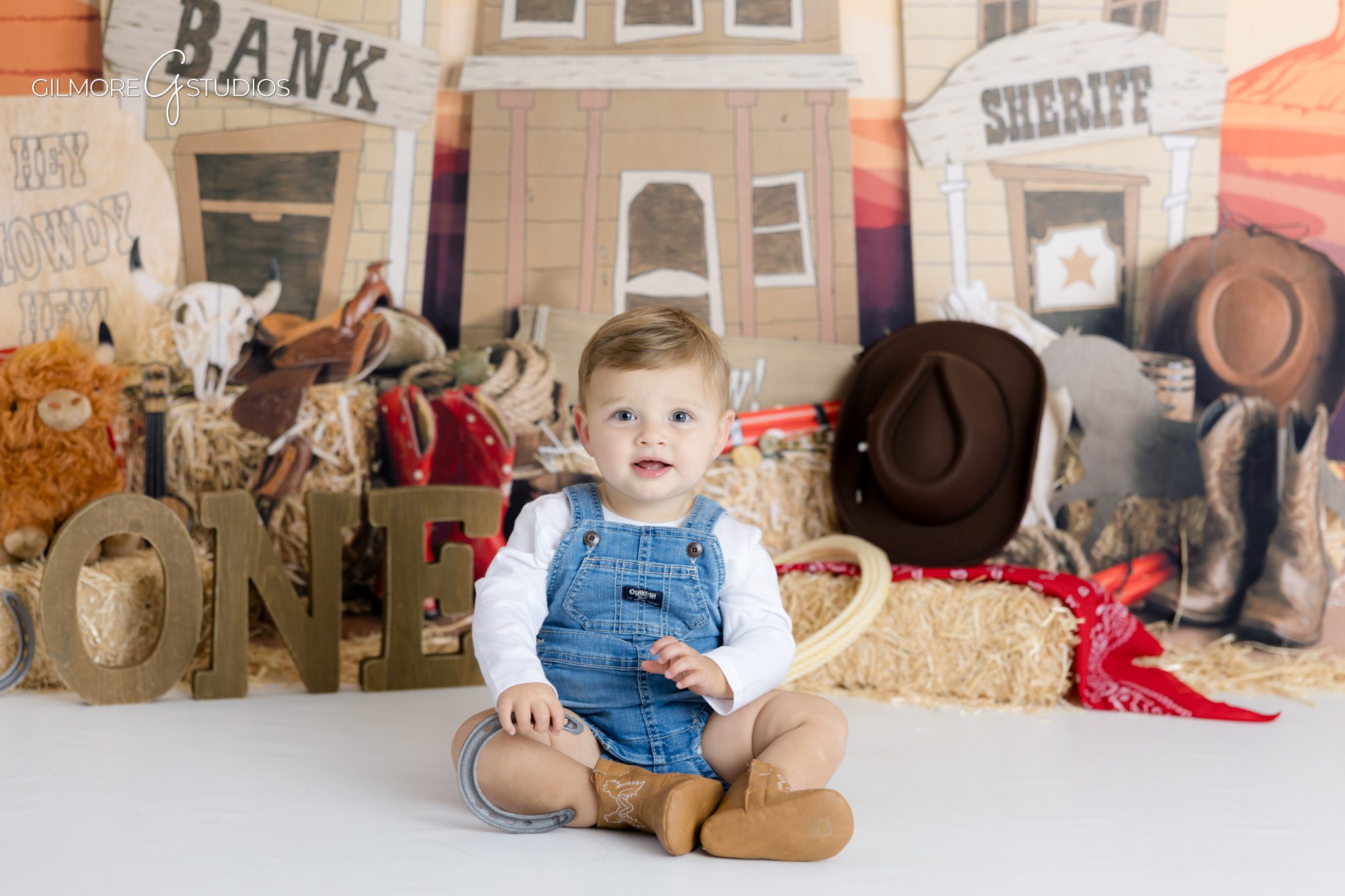 Scottsdale portrait photographer capturing baby in cowboy outfit,

Western cake smash photography with straw hay and barn elements
