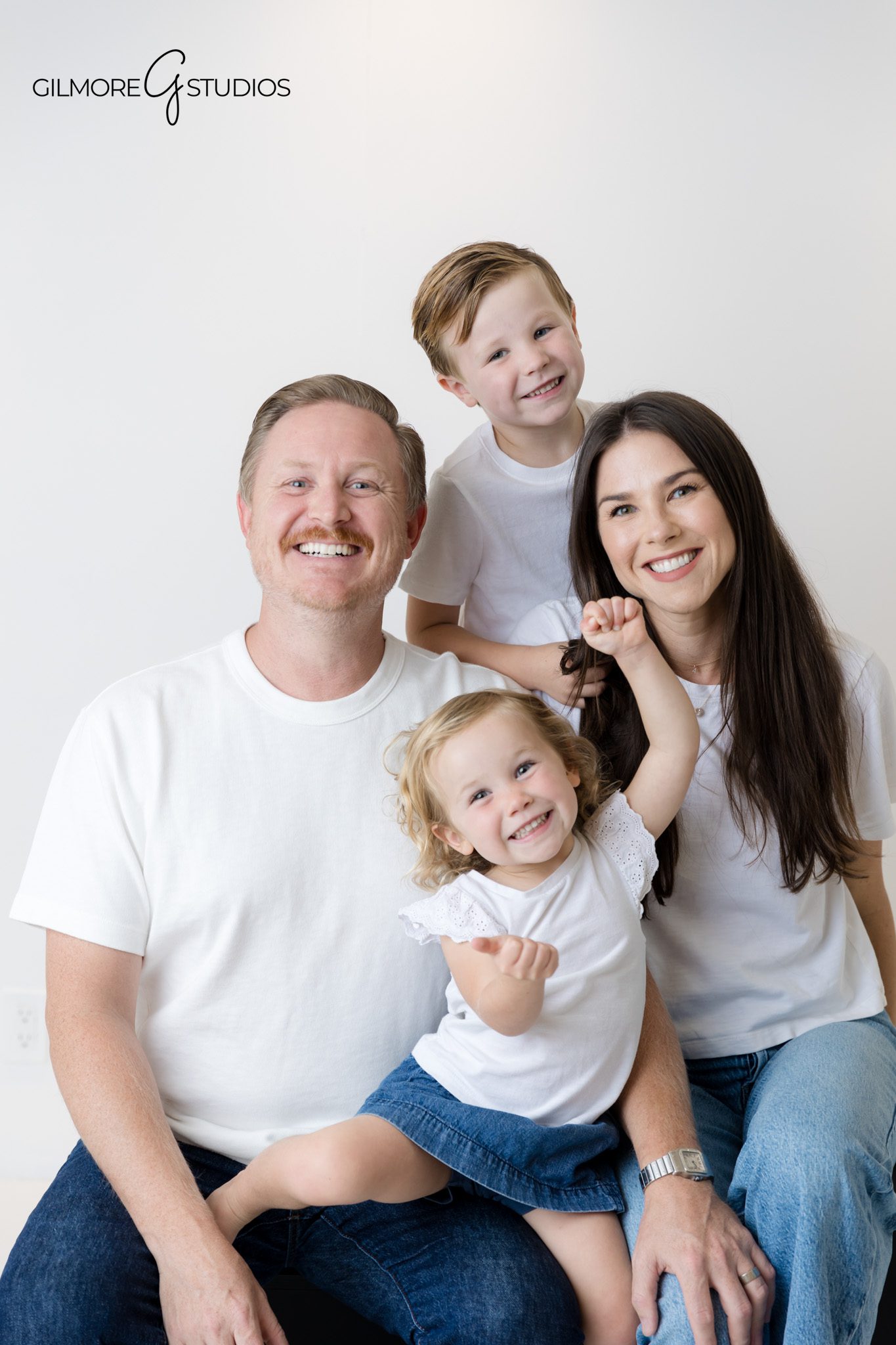 Studio portrait photography featuring parents and kids in white shirts and jeans.

Modern family portraits with minimal styling and bright studio lighting.
