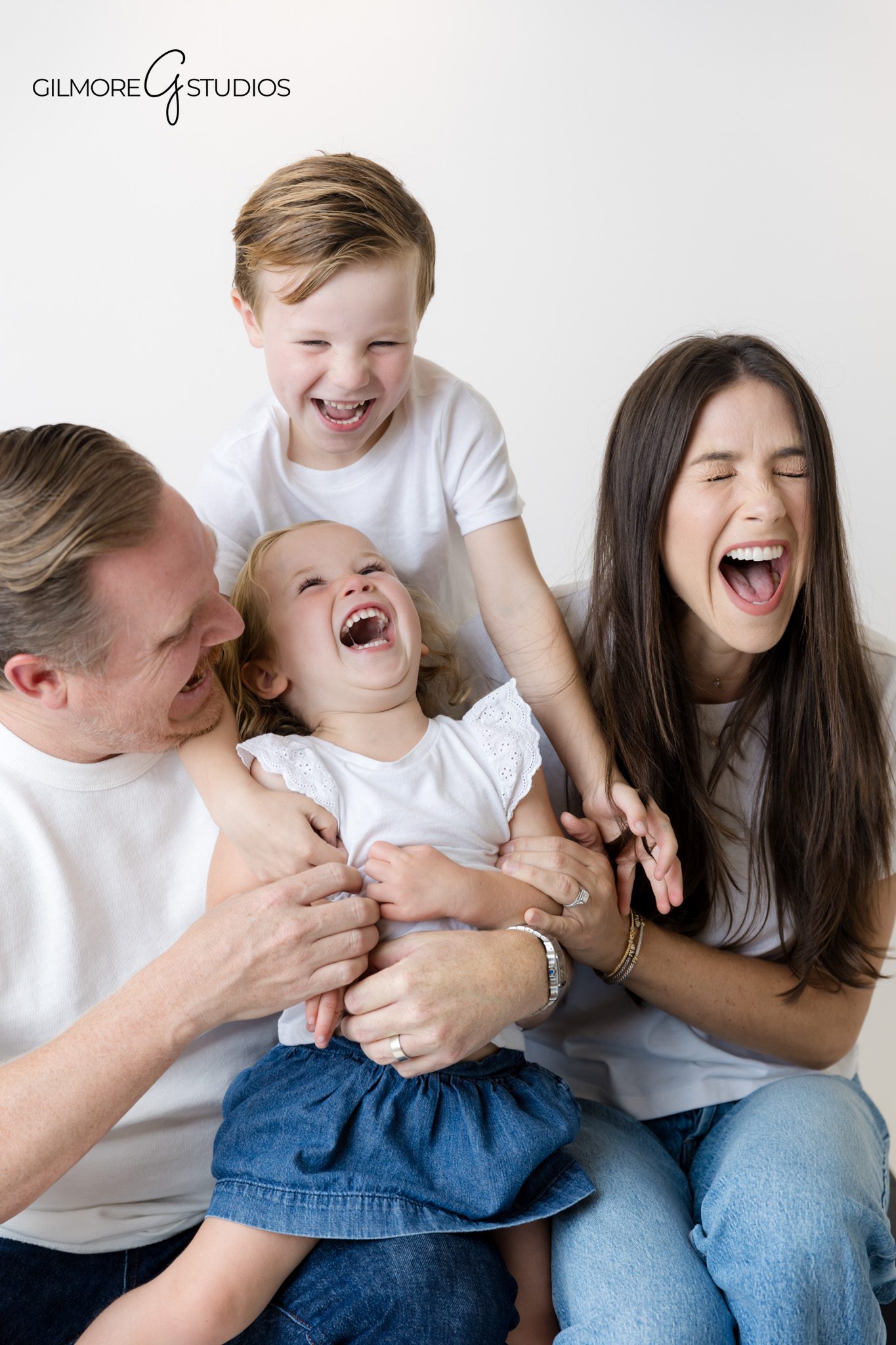 Family portrait photographer documenting clean white background studio session.

Minimalist family photography with modern white shirt and jeans styling.