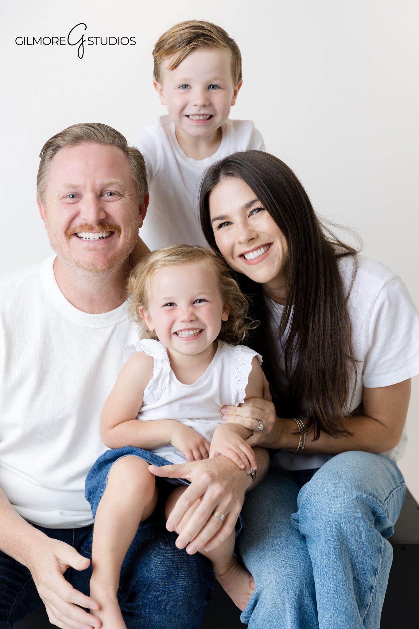 Orange County portrait photographer capturing relaxed family poses in studio.

Professional family photography with matching denim and white outfits.