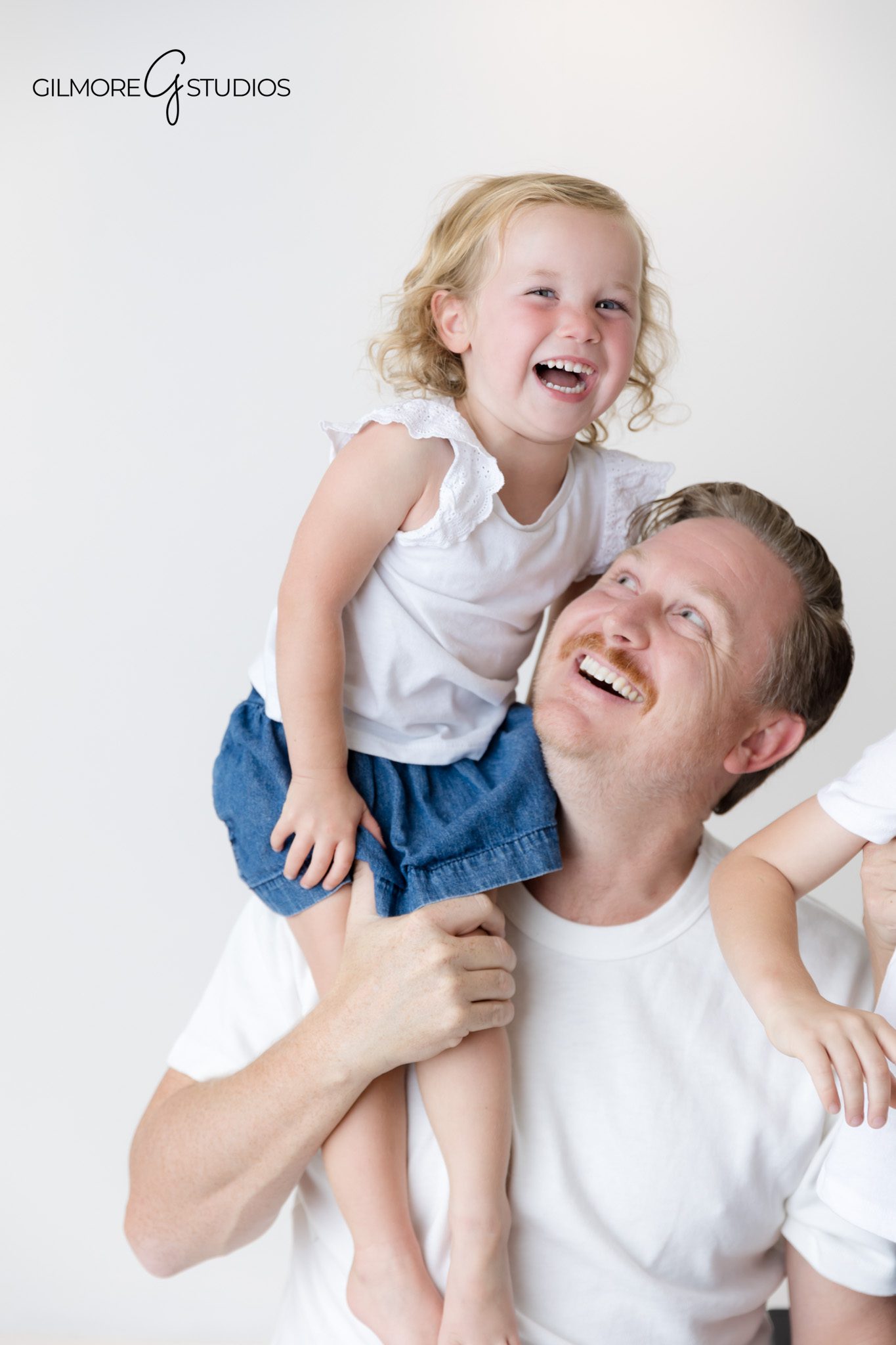 Modern studio portrait of family in matching white shirts and denim.

Family photographer capturing classic studio arrangement in white room.