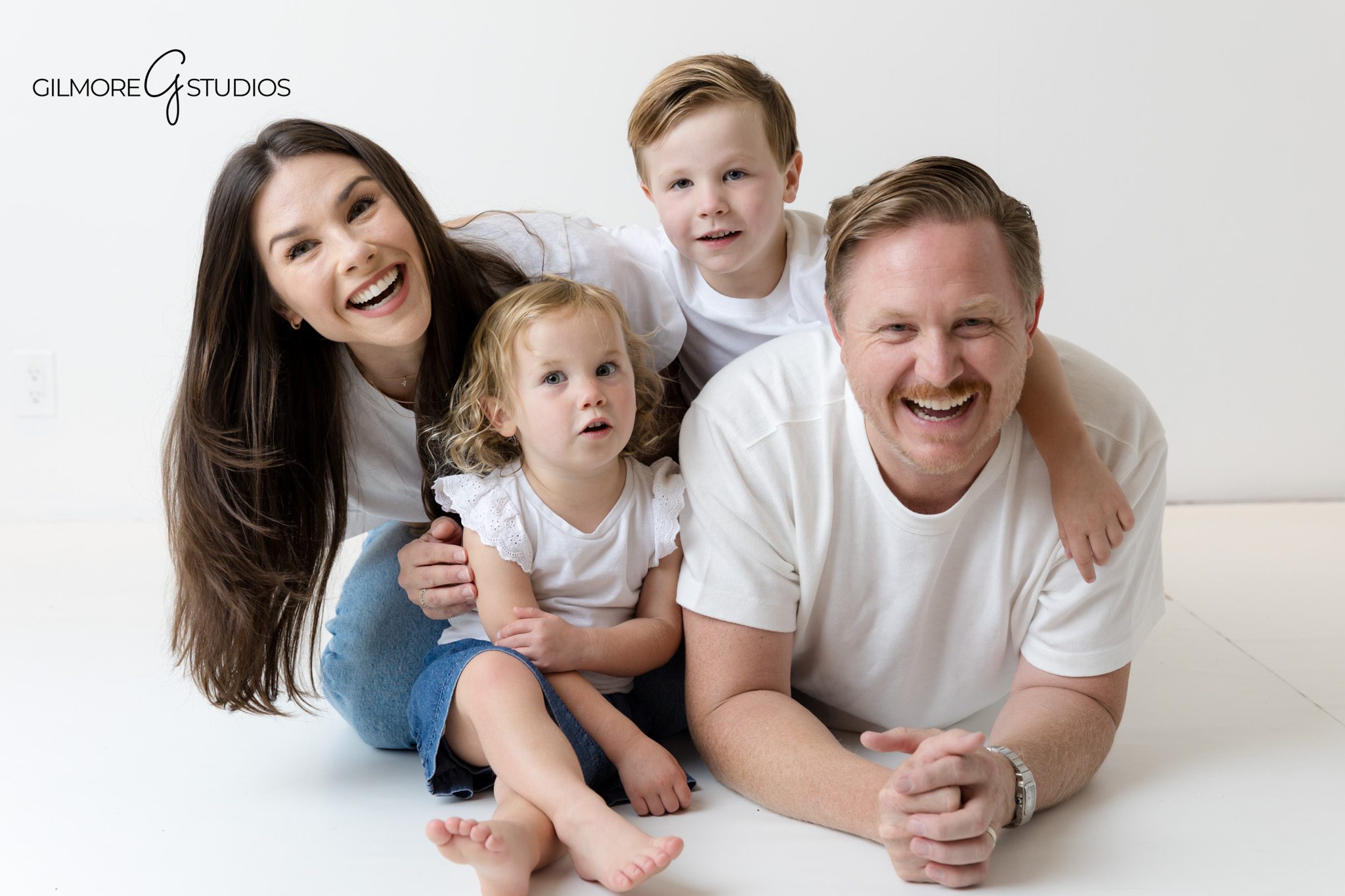 Orange County family photographer capturing studio portraits in matching white shirts and jeans.

Studio family photography with coordinated white tops and denim outfits.