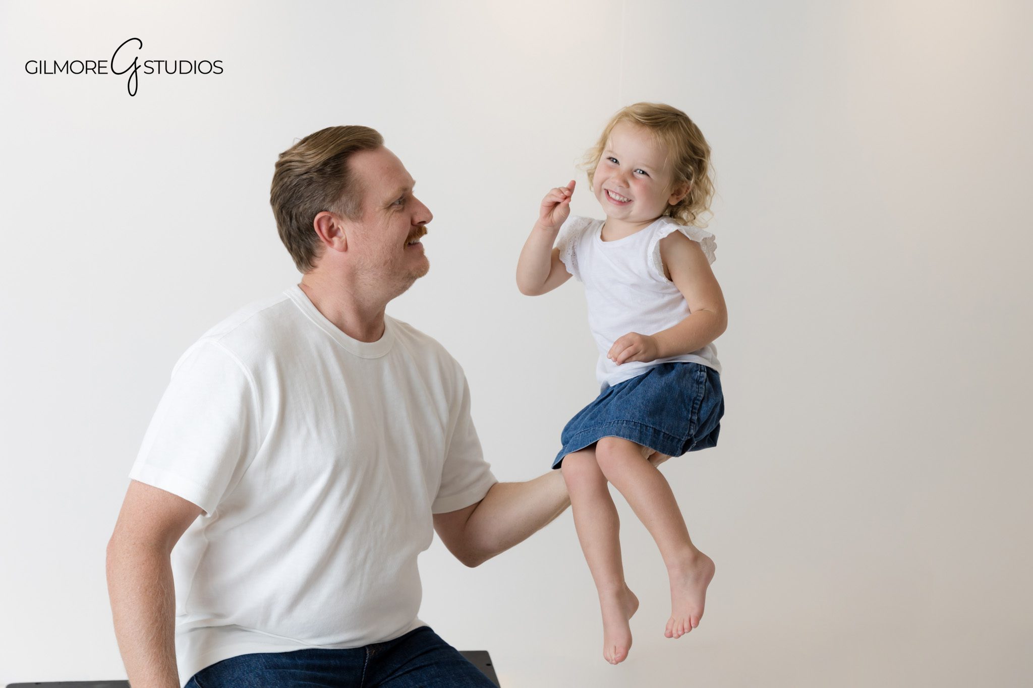 Family portrait photographer capturing relaxed studio moments.

White background photography showcasing coordinated family fashion.