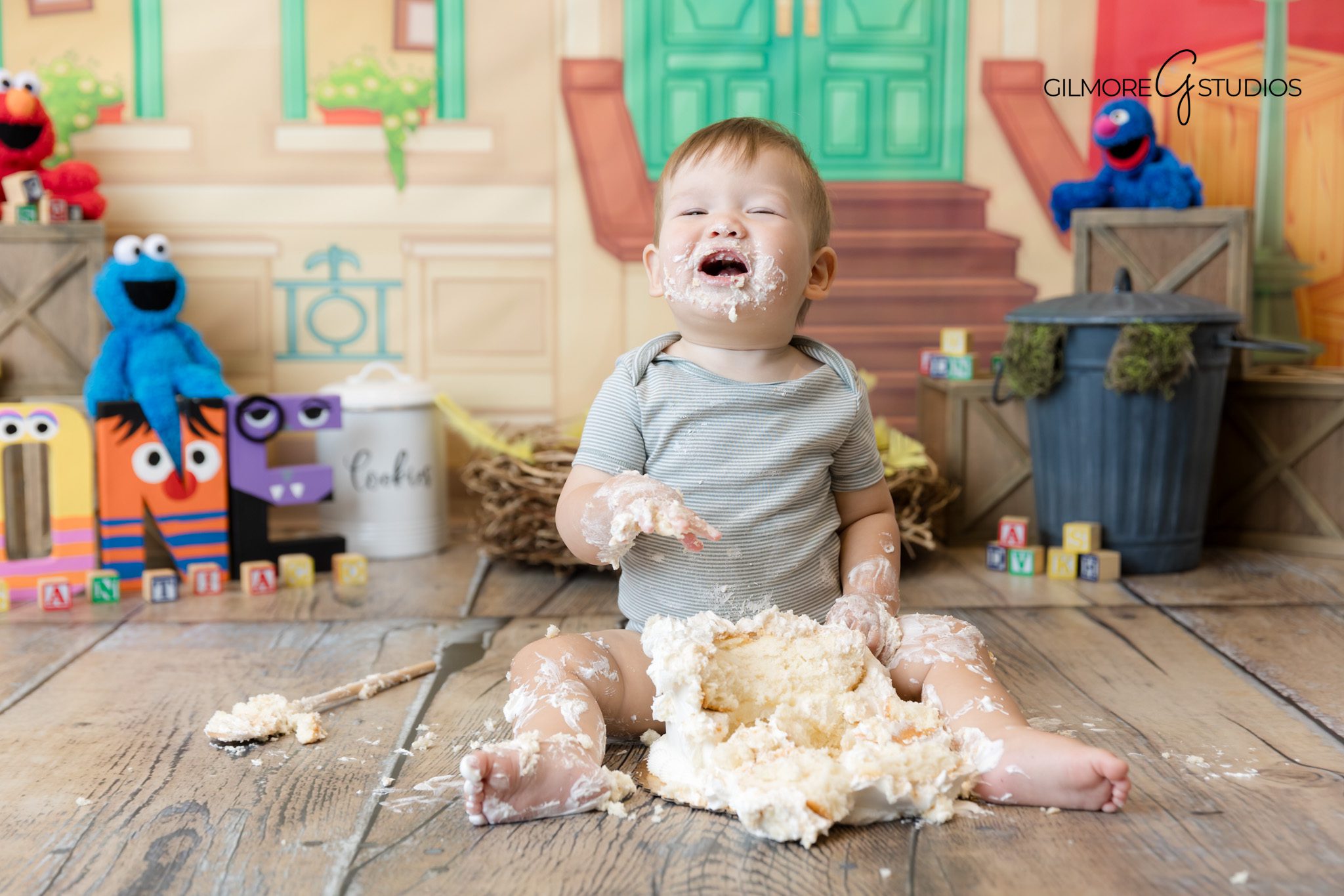 First birthday photography showing rainbow balloon backdrop.

Studio photographer capturing baby enjoying cake smash.