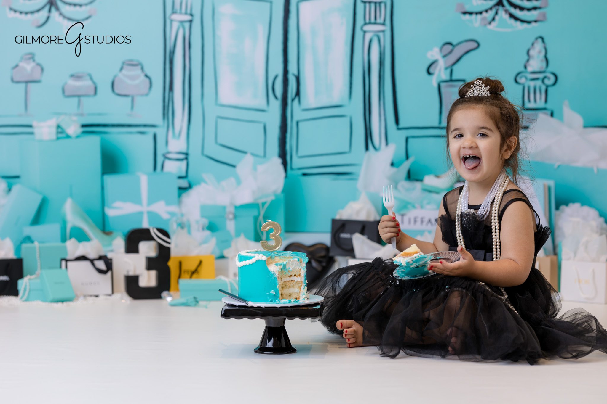 Tiffany birthday setup photographed with pearl and bow decorations.
Studio photography capturing three year old in Tiffany birthday dress.