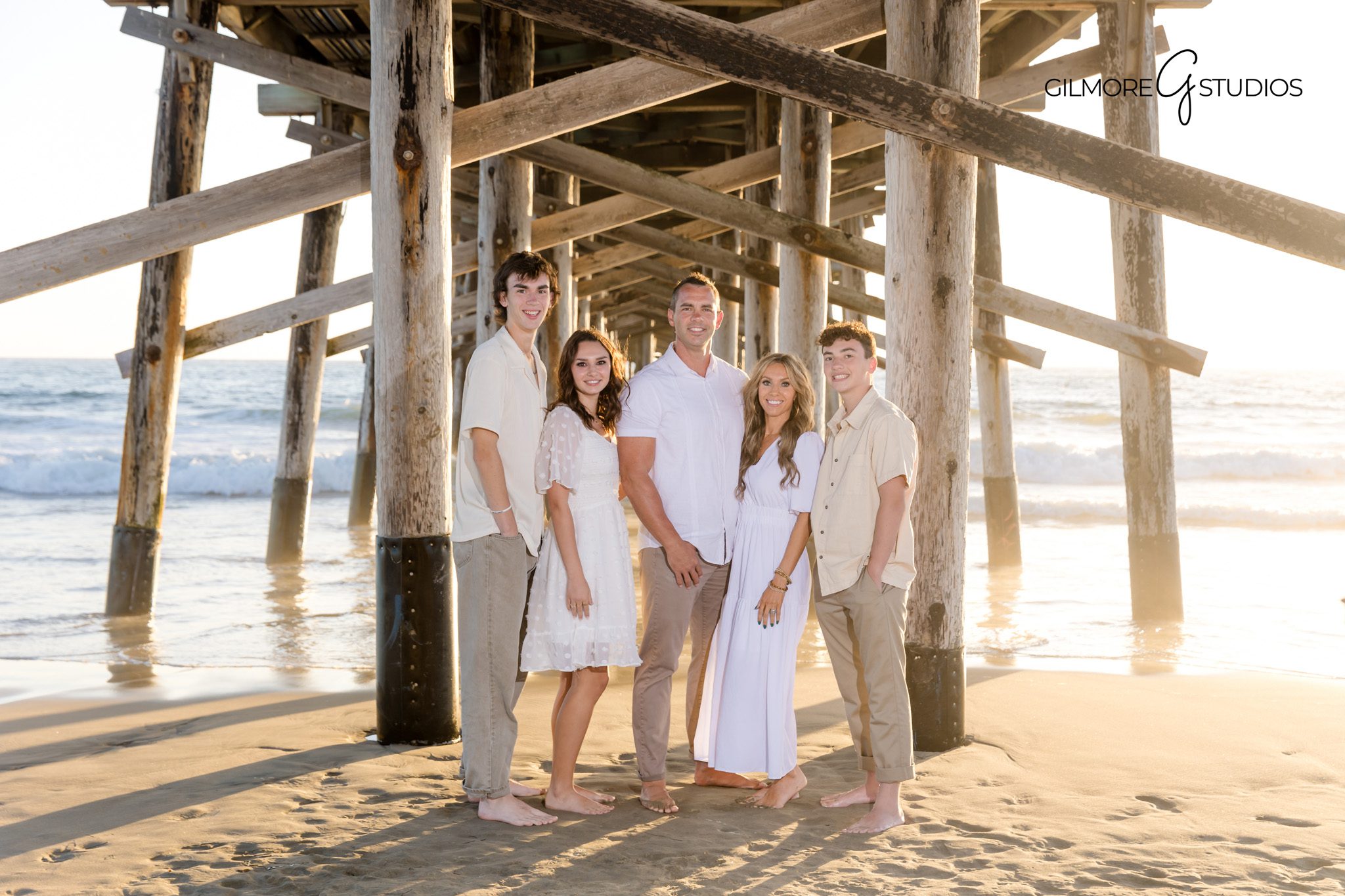 Family holding hands in sunset beach photography near Newport Pier.
Newport Beach Pier sunset portraits with natural light photographer.