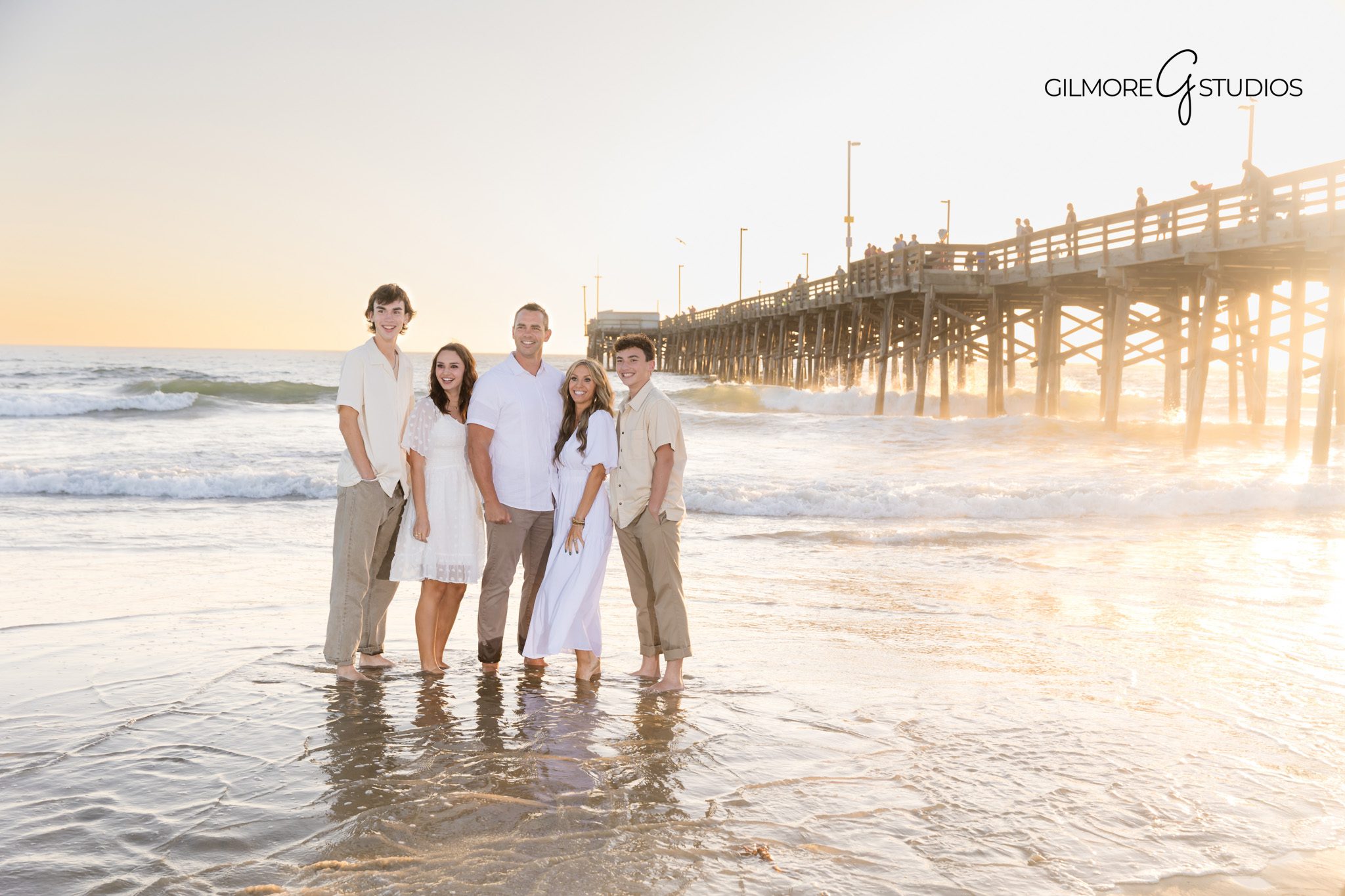 Family portrait photography with pink and orange sunset skies in Newport.
Newport Beach Pier family photos with warm natural lighting.